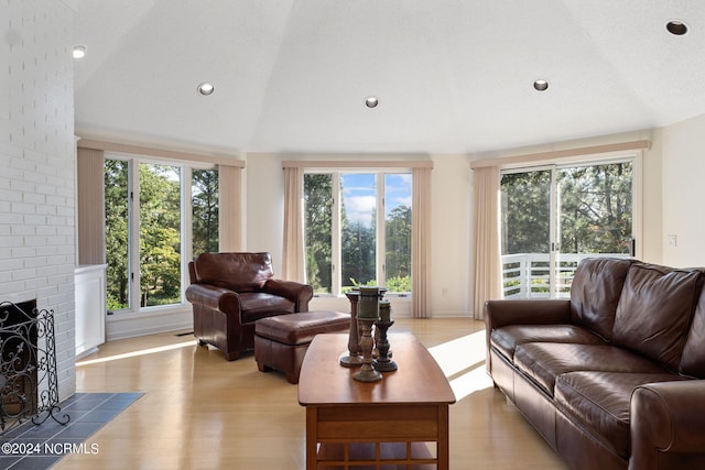 living room featuring light wood-type flooring, a healthy amount of sunlight, a fireplace, and a textured ceiling