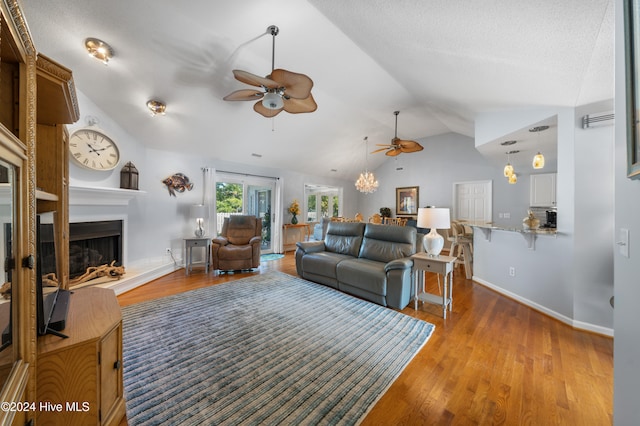 living room with ceiling fan, lofted ceiling, a textured ceiling, and light hardwood / wood-style floors