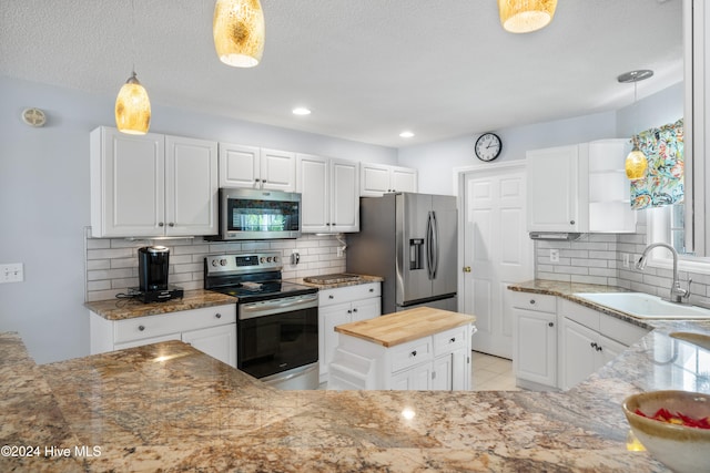 kitchen with white cabinetry, decorative light fixtures, and stainless steel appliances