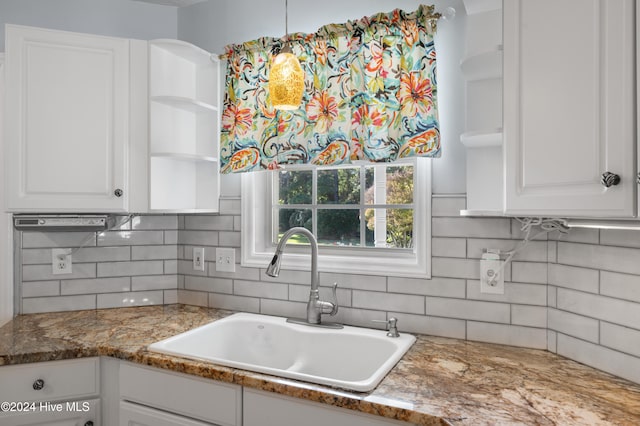 kitchen with white cabinets, decorative backsplash, dark stone counters, and sink