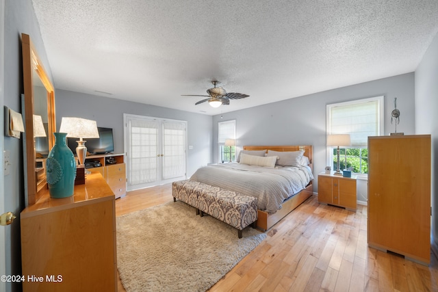 bedroom with light wood-type flooring, multiple windows, and a textured ceiling