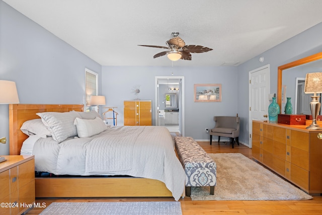 bedroom with hardwood / wood-style floors, ceiling fan, and ensuite bath