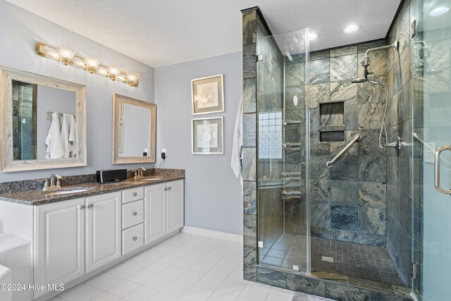 bathroom with tile patterned flooring, vanity, a textured ceiling, and a shower with shower door