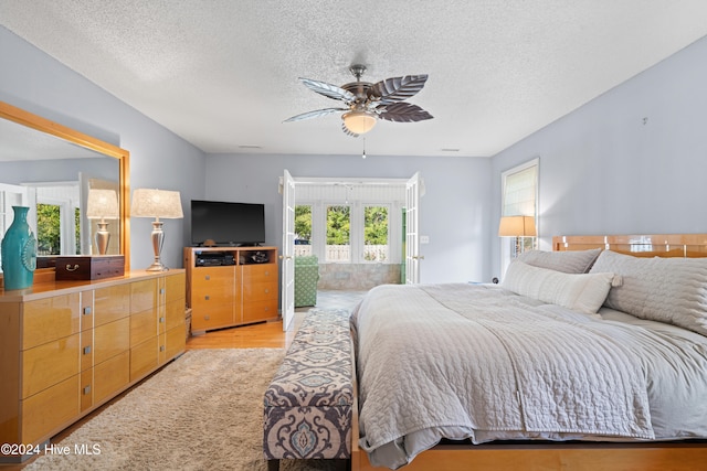 bedroom with ceiling fan, multiple windows, a textured ceiling, and light hardwood / wood-style floors