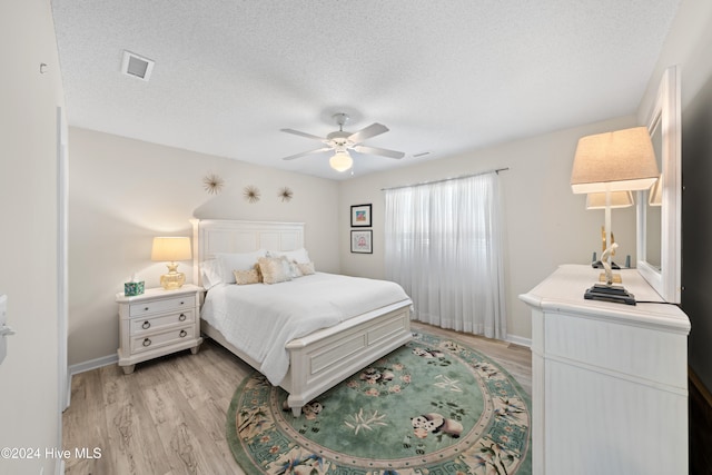 bedroom with ceiling fan, a textured ceiling, and light hardwood / wood-style flooring