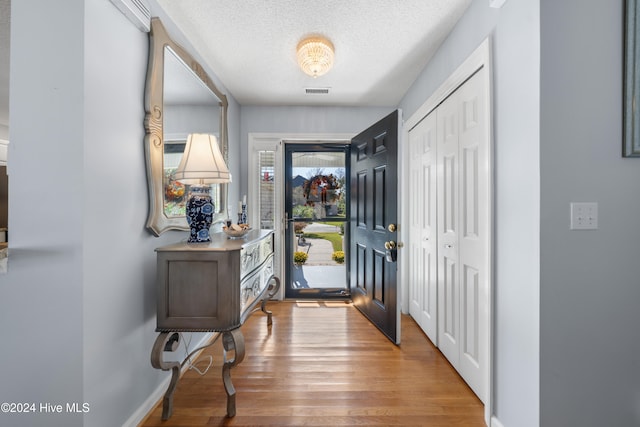 entrance foyer with a textured ceiling, hardwood / wood-style flooring, and a wall mounted AC