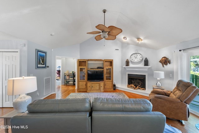 living room featuring light hardwood / wood-style flooring, lofted ceiling, and ceiling fan