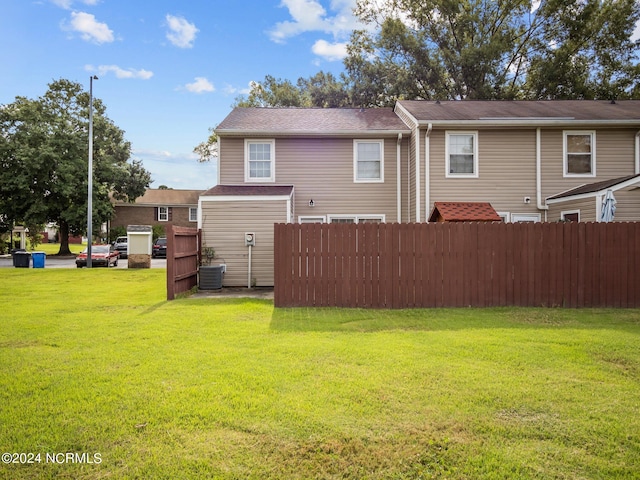 rear view of house with a yard and central AC