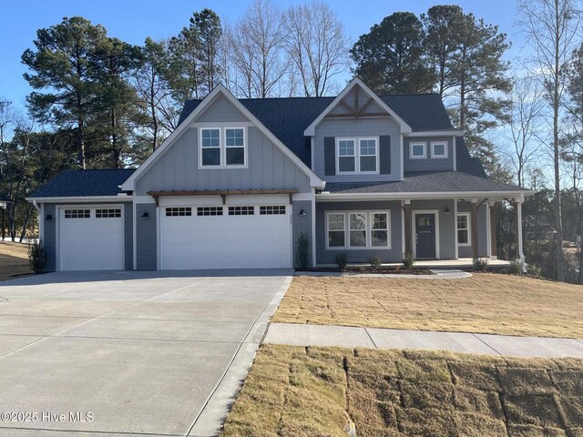 view of front of property featuring a front yard, a garage, and covered porch