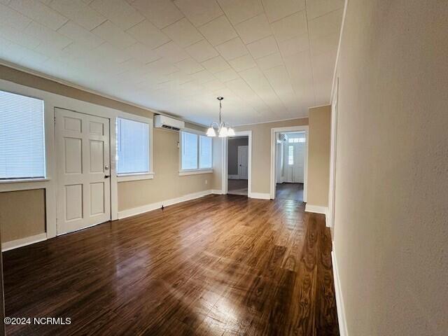 interior space with ornamental molding, hardwood / wood-style floors, a chandelier, and a wall unit AC