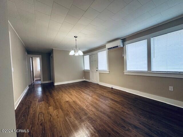 interior space with a chandelier, dark wood-type flooring, and a wall mounted AC