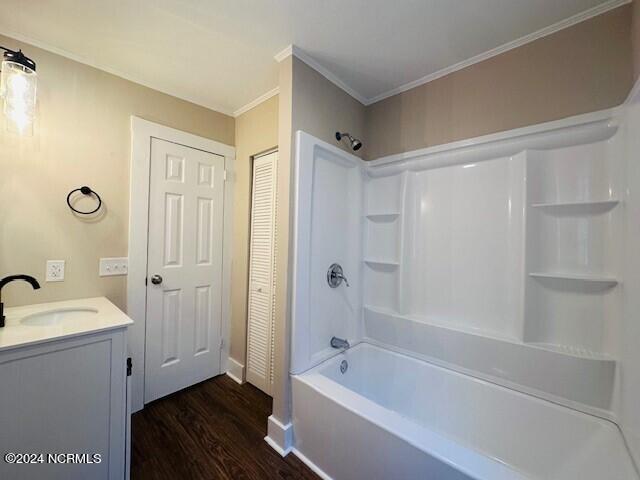 bathroom with crown molding, washtub / shower combination, vanity, and wood-type flooring