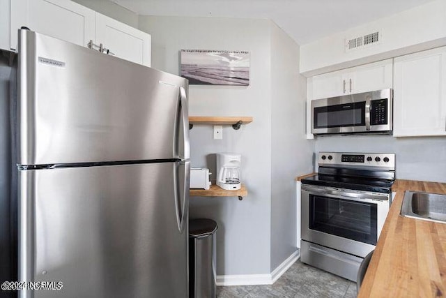 kitchen with wooden counters, stainless steel appliances, and white cabinets