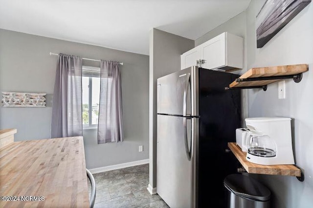 kitchen with stainless steel fridge and white cabinets