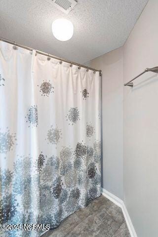 bathroom with a shower with curtain and a textured ceiling