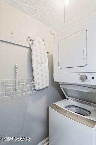 washroom with stacked washer and clothes dryer and a textured ceiling