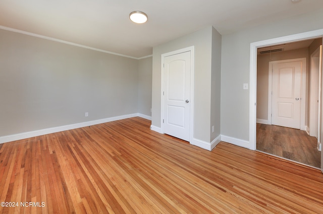 empty room with ornamental molding and light wood-type flooring