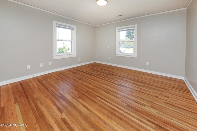 unfurnished room featuring ornamental molding, light wood-type flooring, and a wealth of natural light