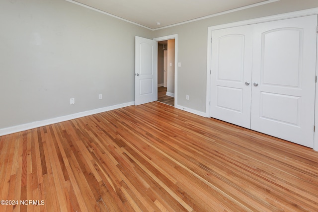 unfurnished bedroom featuring a closet, light hardwood / wood-style flooring, and ornamental molding