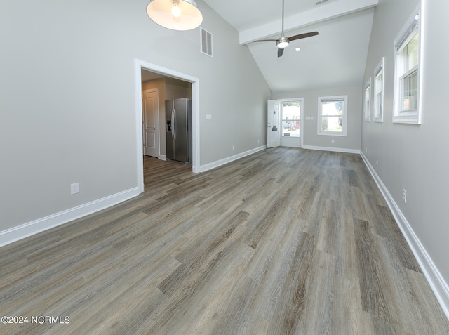 unfurnished living room featuring light hardwood / wood-style floors, beam ceiling, ceiling fan, and high vaulted ceiling