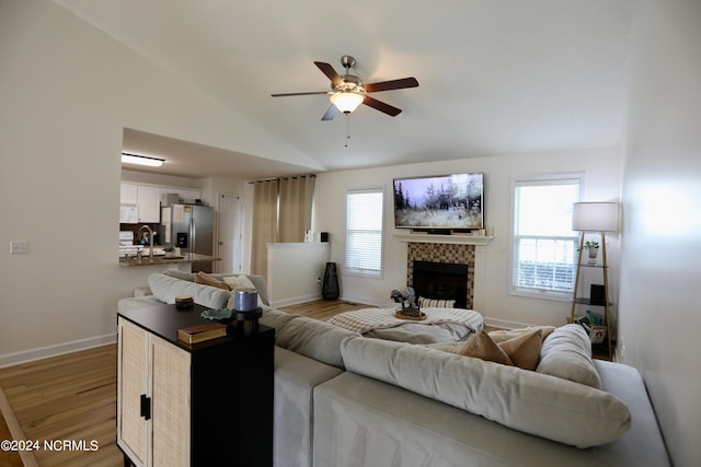 living room featuring light wood-type flooring, vaulted ceiling, ceiling fan, and plenty of natural light