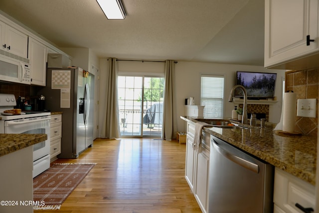 kitchen with dark stone counters, sink, white cabinetry, light hardwood / wood-style flooring, and appliances with stainless steel finishes