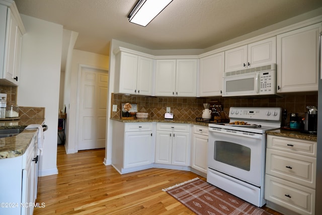 kitchen with light wood-type flooring, tasteful backsplash, white cabinets, white appliances, and dark stone countertops