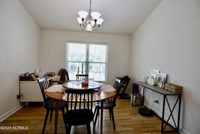 dining area with light hardwood / wood-style flooring, vaulted ceiling, and an inviting chandelier