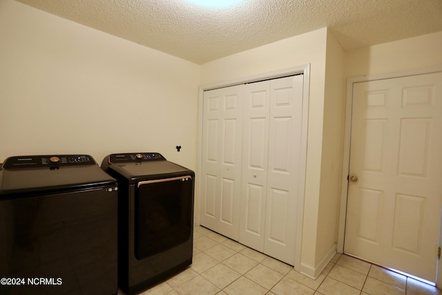 washroom featuring light tile patterned floors, a textured ceiling, and washer and clothes dryer