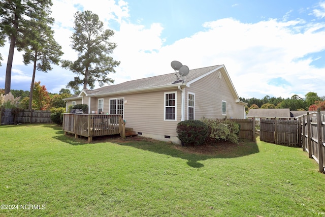 back of property with a deck and a yard