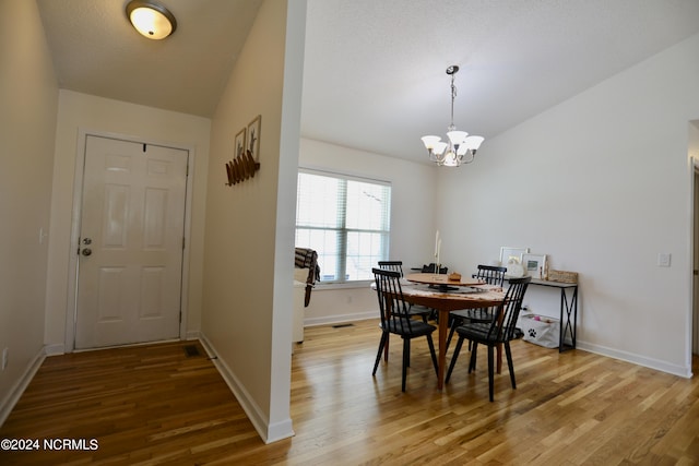 dining space featuring hardwood / wood-style flooring, lofted ceiling, and a notable chandelier