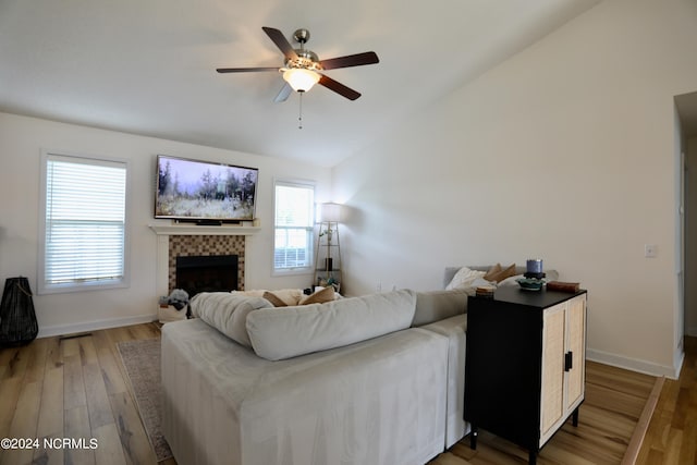 living room with lofted ceiling, ceiling fan, a tile fireplace, and hardwood / wood-style floors