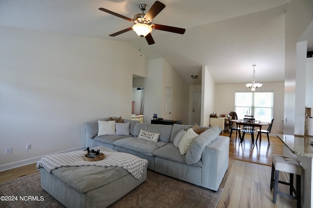 living room with ceiling fan with notable chandelier, vaulted ceiling, and hardwood / wood-style flooring