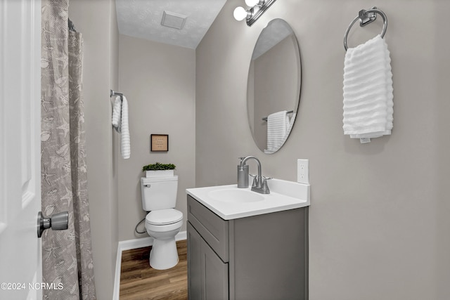 bathroom with wood-type flooring, a textured ceiling, a shower with shower curtain, vanity, and toilet