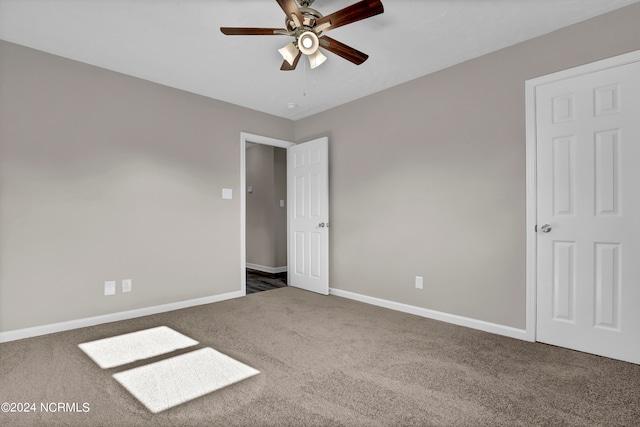 unfurnished bedroom with dark colored carpet and ceiling fan