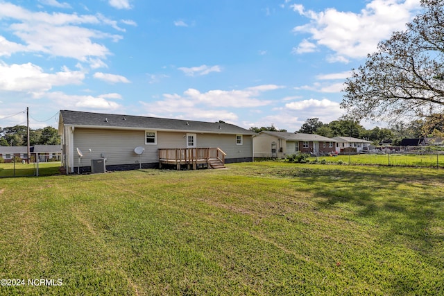 rear view of house with a lawn, central AC, and a wooden deck