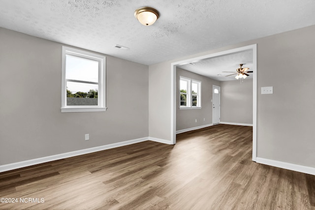 empty room with a textured ceiling, hardwood / wood-style floors, and ceiling fan