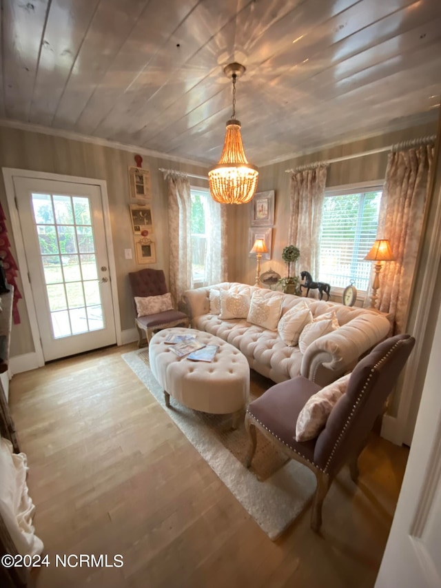 living room with a healthy amount of sunlight, hardwood / wood-style floors, an inviting chandelier, and ornamental molding