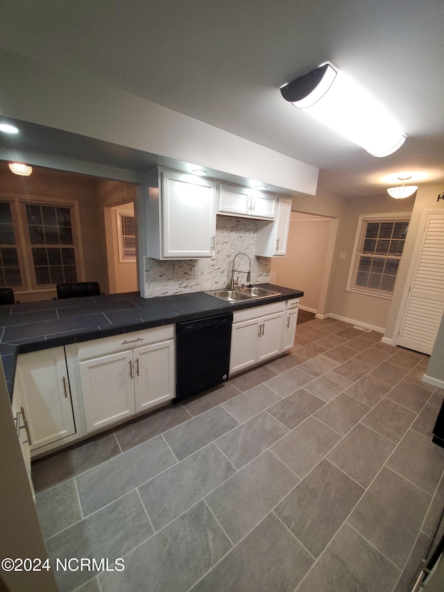 kitchen with black dishwasher, sink, and white cabinetry