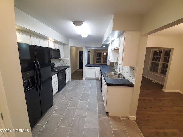 kitchen with tasteful backsplash, dark hardwood / wood-style flooring, sink, white cabinets, and black appliances