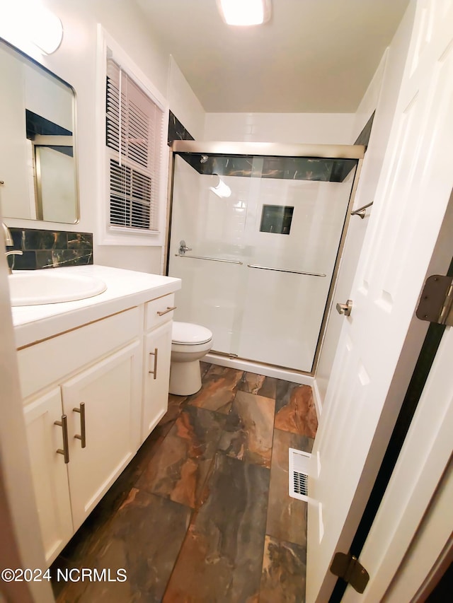 bathroom with toilet, vanity, and an enclosed shower