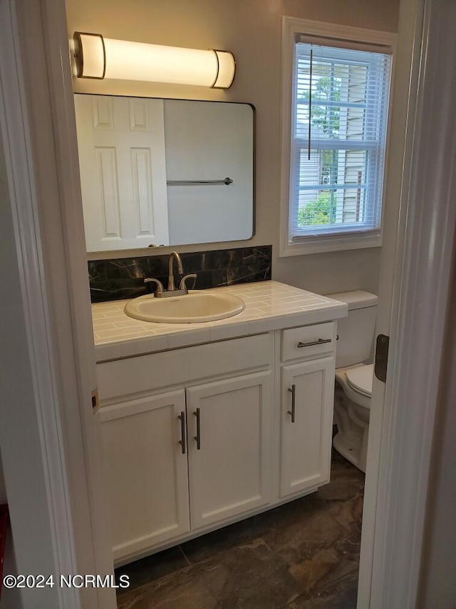 bathroom featuring backsplash, vanity, and toilet