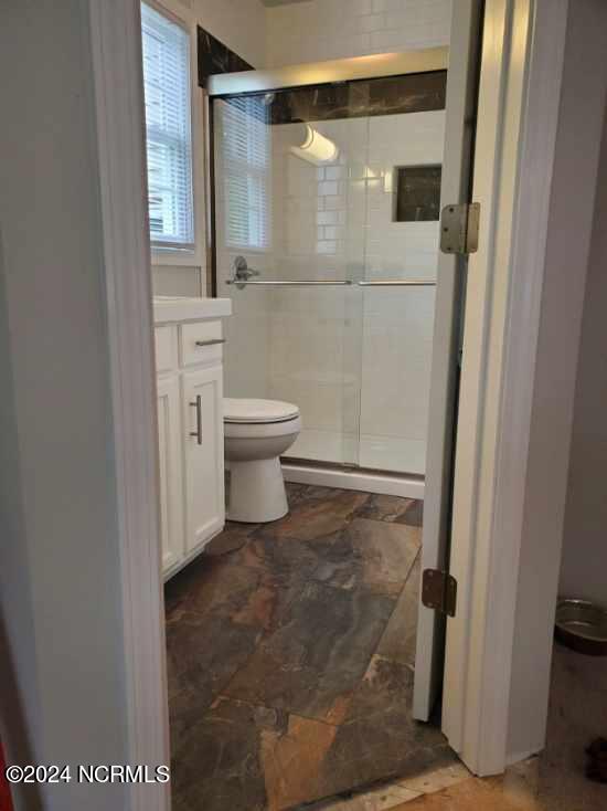 bathroom with an enclosed shower, toilet, and vanity