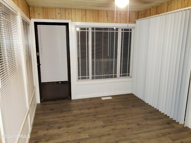 unfurnished room featuring wooden walls and dark wood-type flooring