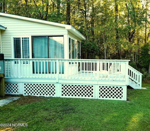 rear view of property with a lawn, a wooden deck, and a sunroom