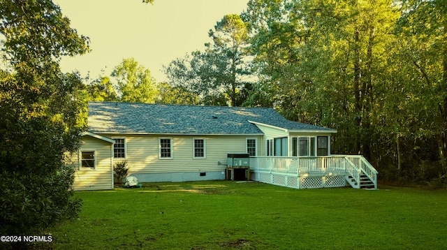 back house at dusk with a wooden deck and a lawn