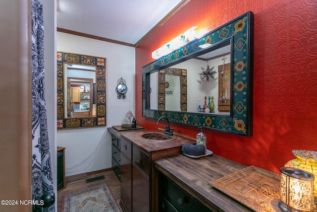 bathroom with ornamental molding, a textured ceiling, and vanity