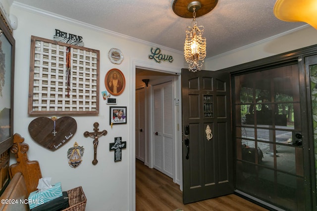 foyer featuring an inviting chandelier, a textured ceiling, crown molding, and dark hardwood / wood-style flooring