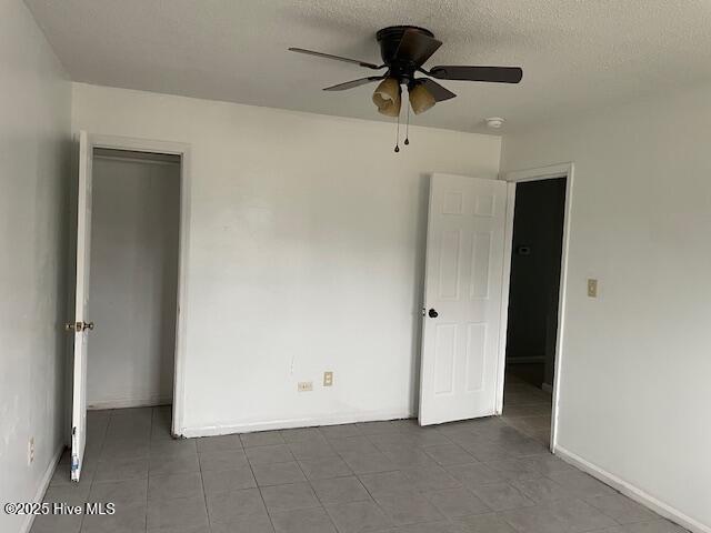 unfurnished bedroom featuring ceiling fan, tile patterned flooring, a closet, and a textured ceiling