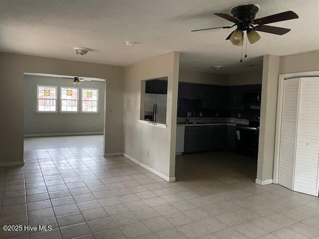 kitchen featuring sink, stainless steel fridge with ice dispenser, a textured ceiling, ceiling fan, and stove